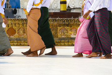 (selective focus) Some Burmese Buddhist faithful are walking barefoot around the Shwedagon Pagoda...