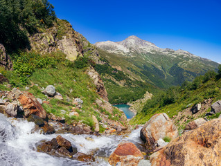 Large panorama, the river flows from the mountains into the lake. The Caucasus Mountains on a summer, clear day. Tourie Lake in the Outskirts of Dombai. .