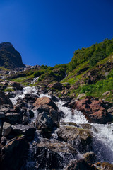 The river flows among the stones from the mountain in the surroundings of Dombai. The Caucasus Mountains on a summer, clear day. Tourie Lake.