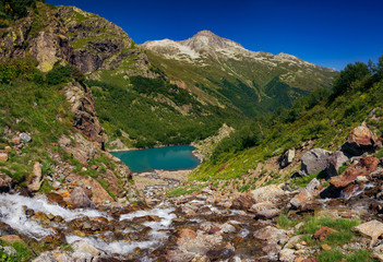 Large panorama, the river flows from the mountains into the lake. The Caucasus Mountains on a summer, clear day. Tourie Lake in the Outskirts of Dombai. .