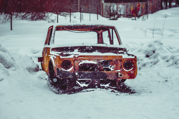 One old abandoned rusty and broken car in snow in Russian winter forest under a tree. Toned in color.