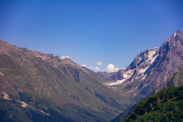 Fototapeta premium Peaks of mountains in the neighborhood of Dombai. Caucasus Mountains summer, clear day from the forest.