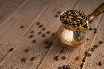 Close up of fresh roasted coffe beans in  cezve (traditional turkish coffee pot) on wooden table.