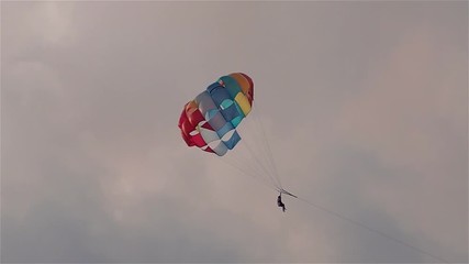 Parasailing in evening. Bright parachute on a background of a sky.