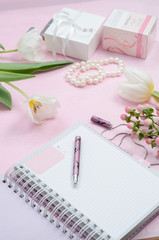 Women's accessories in white and pink colors, flowers, notebook with pen, cosmetics and gift boxes. Beauty women flat lay.