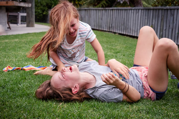 girls enjoying rough and tumble play on the grass at home