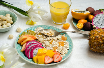 Healthy breakfast. Fresh muesli with yogurt, tropical fruits and nuts on white background.