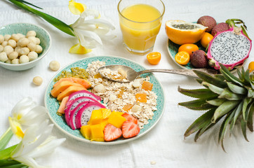 Healthy breakfast. Fresh muesli with yogurt, tropical fruits and nuts on white background.