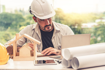 Young man architect or engineer working at desk with designer equipment to make interior design at...