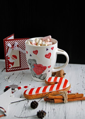 coffee mug with marshmallow greeting card and gingerbread on wooden background holiday mood