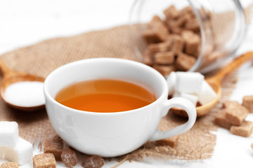 Obraz na płótnie Canvas Glass cup of hot tea with sugar on the table