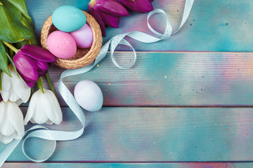 Easter eggs with tulips on blue wooden background
