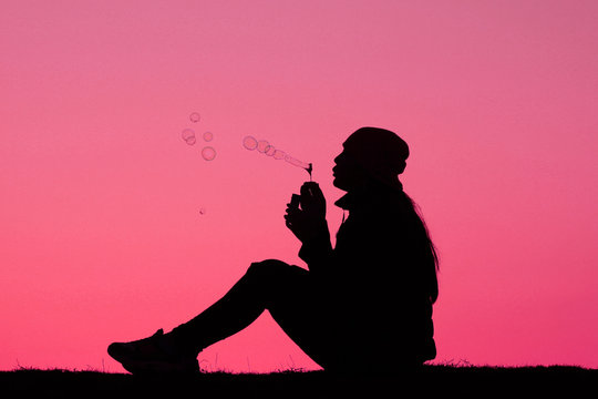girl blows soap bubbles on a bright pink background, fashionable background, girl silhouette