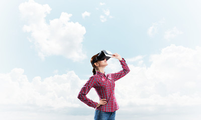 Girl in checked shirt wearing VR glasses experiencing another reality