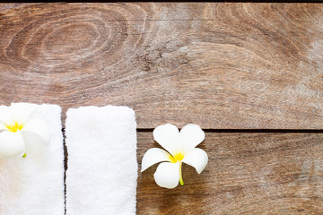 Fototapeta na wymiar White towel with white flower on vintage wooden background, spa concept