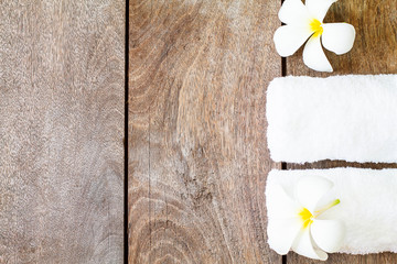 White towel with white flower on vintage wooden background, spa concept