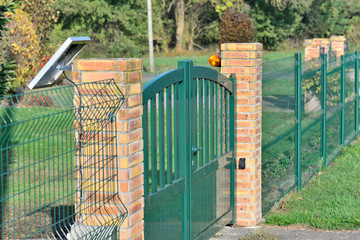 fence with a green electric gate way in a garden
