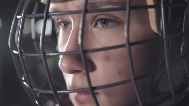 Handsome hockey player. dark arena, close up portrait of defender or forward canadian player