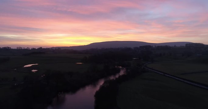 Aerial shot of colorful sunrise over a river in the valley.