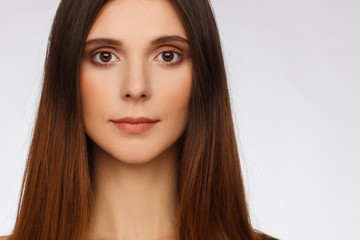 Fototapeta premium Portrait of a beautiful woman with straight long hair and interesting emotion. Light gray background