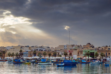 Sun rays over ancient fisher village Marsaxlokk, Malta
