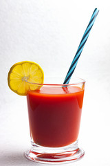 ZUMO DE TOMATE EN VASO DE CRISTAL CON LIMÓN SOBRE FONDO BLANCO.