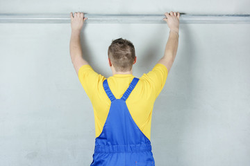 The builder carefully corrects the irregularities of the wall. Builder in work clothes against a...