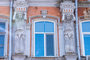 Fototapeta na wymiar Saratov, Russia, March 14, 2019: Facade of a 19th century building with barrels of men supporting a roof, Vintage house facade - Russian provincial architecture