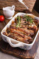 Grilled pork ribs. Meat with spices and herbs in dishes on wooden background. Lunch barbecue with salad and sauce. Free space for the text