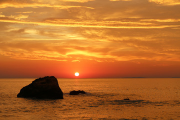 Orange sky over the Ionian sea with rock at sunset (Greece)