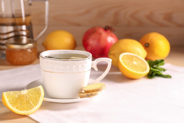 Cup of hot tea with lemon and ginger on table