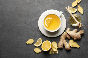 Obraz na płótnie Canvas Cup of tasty tea with lemon, ginger and honey on grey background