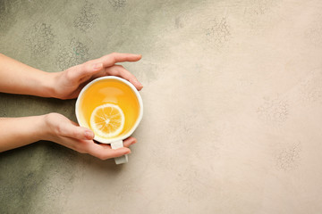 Female hands with cup of tasty tea on light background
