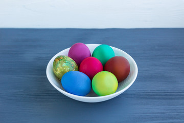 White plate with Easter multicolored boiled eggs on grey wood