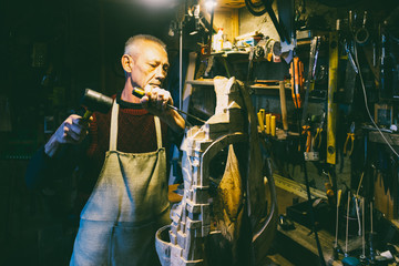 Master carpenter 50 - 55 years old creates wooden sculpture in the workshop