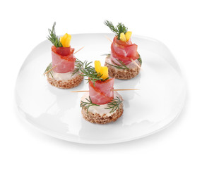 Plate with tasty canapes on white background