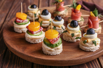 Plate with tasty canapes on table, closeup