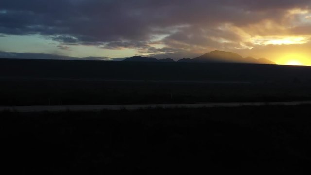 A drone fly's towards the lake dam and rises up to a beautiful sunrise