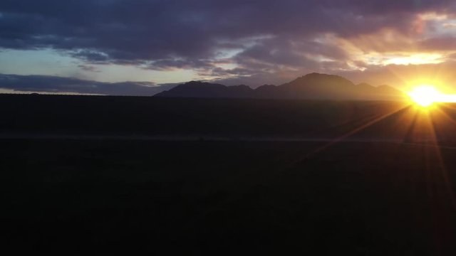 The drone rises form below the dam to reveal the sun shining on the lake