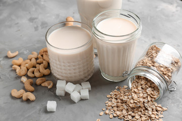 Assortment of tasty vegan milk on grey background