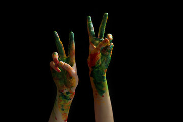 Painted female hands showing victory gesture on dark background