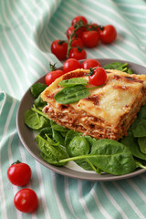 Tasty baked lasagna with basil on plate