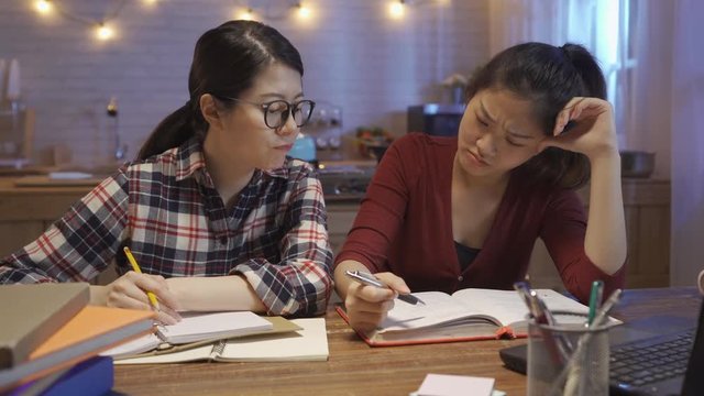 Depressed woman student frowning while prepare for exam not ready less time left. female roommate working partner offering support comforting and keep doing homework in night kitchen dormitory.