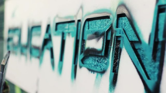 Close up of a spray can artist spraying a stencil as part of a bigger mural
