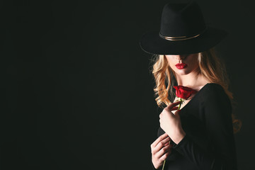 Beautiful young woman with flower on dark background