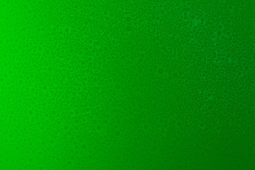 Small droplets of water on a green, matte background illuminated with a delicate light.