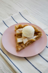 Slice of homemade apple pie with ice cream on pink plate, side view. Close-up.