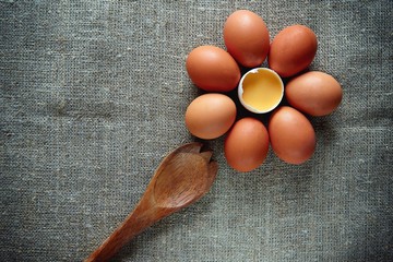 Farm fresh eggs lie on the surface of the table with a wooden spoon, ready-to-cook healthy papneja.