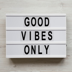 'Good vibes only' words on lightbox over white wooden surface, top view. From above, overhead, flat...