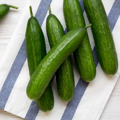 Fresh green cucumbers on white wooden background, overhead view. Flat lay, from above, top view.